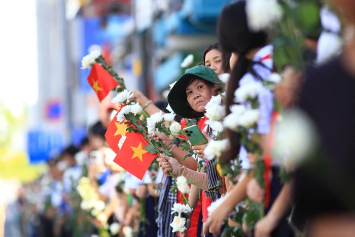 Người dân hai bên đường Điện Biên Phủ dõi theo đoàn xe đưa các liệt sĩ về nơi an nghỉ. Ảnh: Nghĩa Phạm.