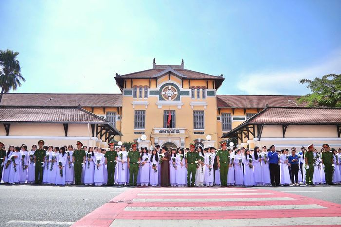  Giáo viên, học sinh tại trường THPT Nguyễn Thị Minh Khai xếp hàng nghiêm trang đợi đoàn xe đi qua. Ảnh: Võ Kỳ. 