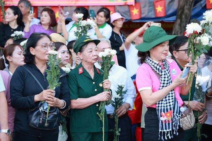 Người dân cầm hoa chờ tiễn đoàn xe đưa liệt sĩ. Ảnh: Mạnh Linh - TTXVN