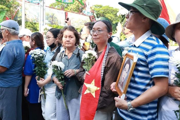 Người dân cầm hoa và di ảnh chờ tiễn đoàn xe đưa liệt sĩ. Ảnh: Mạnh Linh - TTXVN