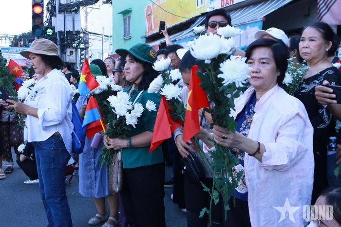 Người dân cầm hoa trắng, cờ Đảng, cờ Tổ quốc, đứng trước Công viên Lê Thị Riêng, thành kính tiễn đưa các anh hùng liệt sĩ về nơi an nghỉ. 