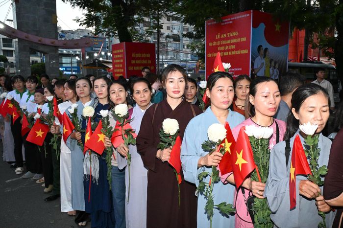 Đông đảo phật tử và người dân cầm nhành hoa trắng, cờ Tổ quốc cầu nguyện tại công viên. Ảnh: VIỆT DŨNG