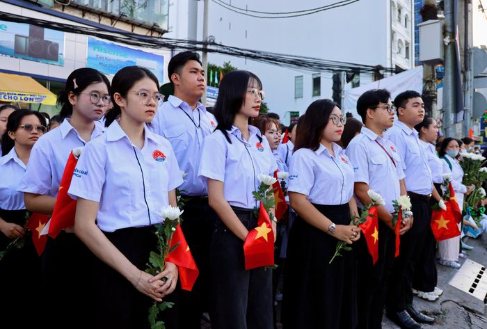  Sinh viên Học viện Cán bộ TPHCM chờ tiễn đoàn xe đưa hài cốt liệt sĩ trên đường Cách Mạng Tháng Tám, phía trước Công viên Lê Thị Riêng. Ảnh: HOÀNG TRIỀU 