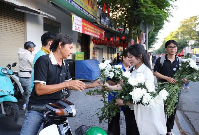  Những nhành cúc trắng được trao tặng người dân trước Công viên Lê Thị Riêng để tiễn đưa các Anh hùng liệt sĩ về nơi an nghỉ. Ảnh: HOÀNG TRIỀU 
