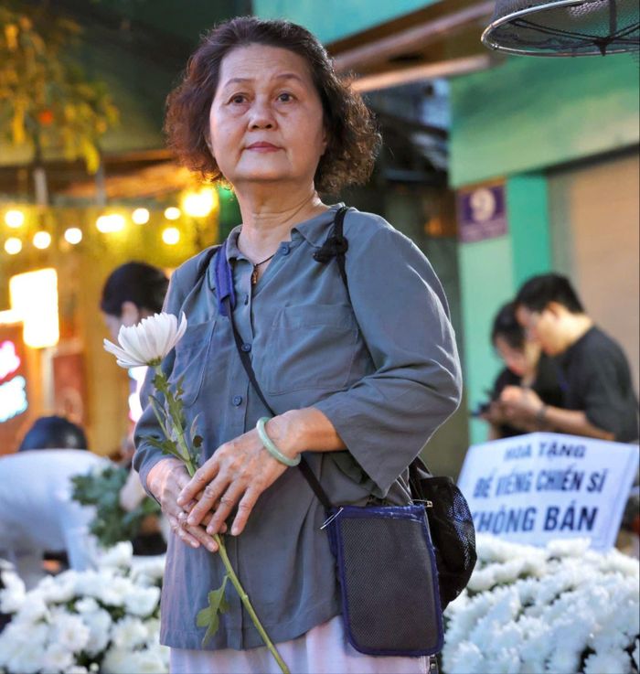  Bà Mỹ Hoa (66 tuổi, ngụ phường Tân Sơn Hòa) cầm nhành cúc trắng, có mặt từ sớm trước Công viên Lê Thị Riêng. Ảnh: HOÀNG TRIỀU 
