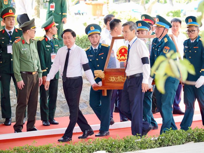 Các đại biểu thực hiện nghi thức đưa hài cốt liệt sĩ đến vị trí an táng. Ảnh: HOÀNG HÙNG