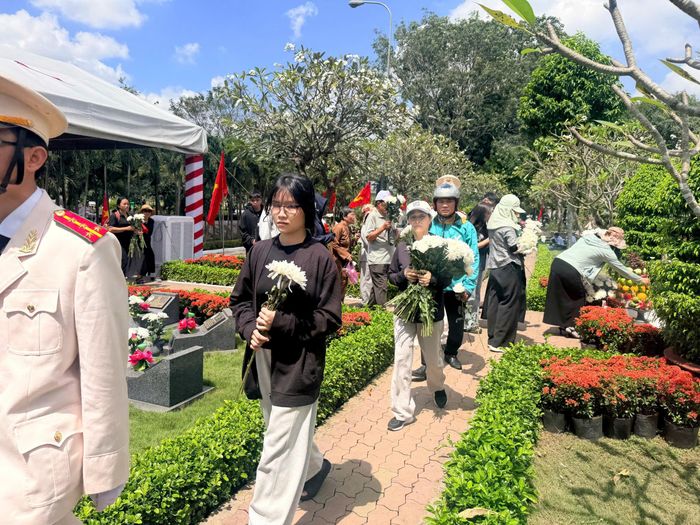 Dòng người mang hoa trắng đến đặt tại các phần mộ, tri ân các liệt sĩ sau lễ an táng. Ảnh: HOÀNG HÙNG
