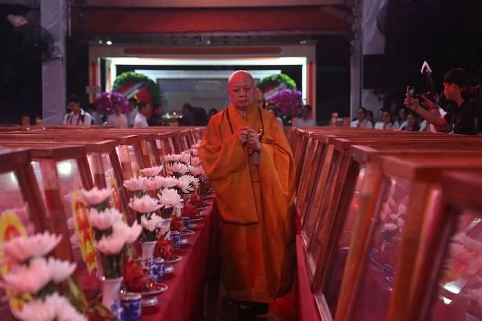 Hòa thượng Thích Lệ Trang cầm nén nhang làm lễ trước chiếc quách đựng bộ hài cốt tập thể, đặt ở vị trí trung tâm nhà quàn. (Ảnh: Nhóm PV)