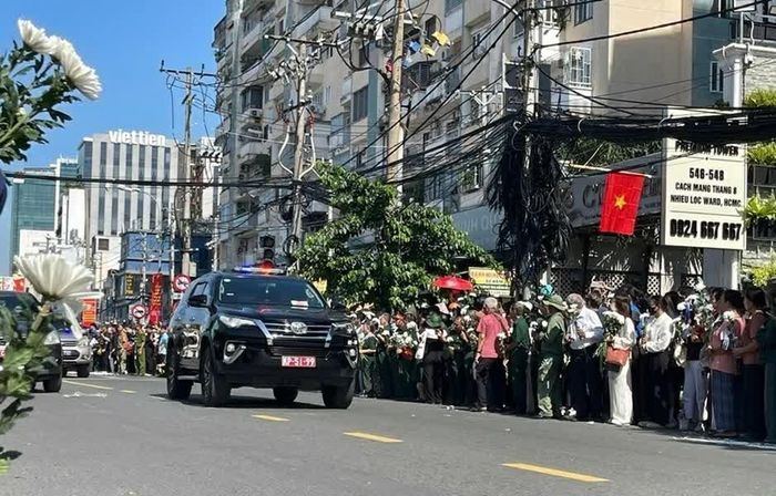 Người dân TP. Hồ Chí Minh cầm hoa trắng tiễn các liệt sĩ về nơi an nghỉ cuối cùng. (Ảnh: TN)