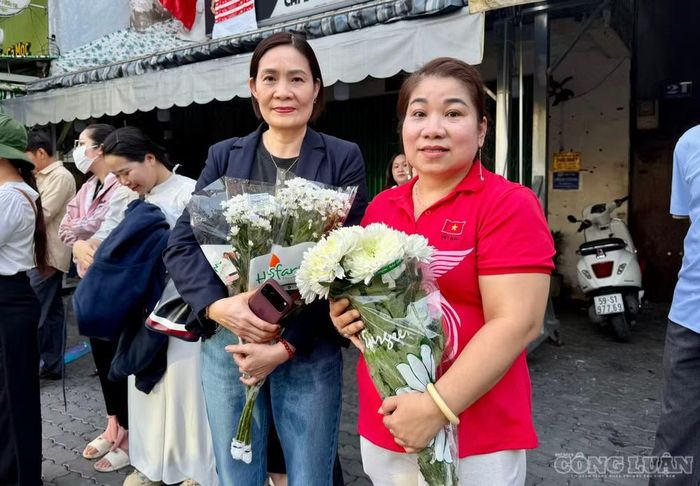 Bà Phạm Thị Trân, 63 tuổi (trái) xúc động ôm bó hoa cúc trắng đứng viếng bên đường