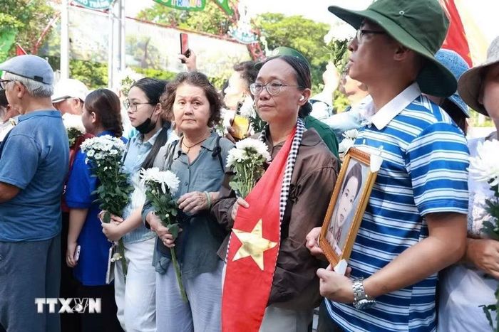 Người dân cầm hoa và di ảnh chờ tiễn đoàn xe đưa liệt sỹ. (Ảnh: Mạnh Minh/TTXVN)