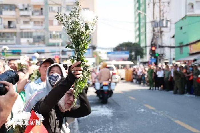 Người dân cầm hoa chờ tiễn đoàn xe đưa liệt sỹ. (Ảnh: Mạnh Minh/TTXVN)