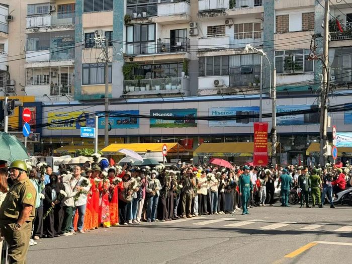 Hàng ngàn người dân xếp hàng tiễn đoàn xe chở hài cốt liệt sĩ “về với đất Mẹ". (Ảnh: PV/Vietnam+)