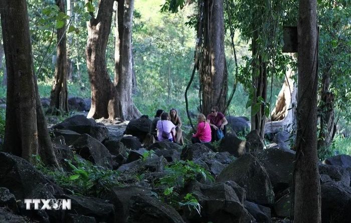 Du khách nước ngoài nghỉ chân ngắm cảnh tại Thác Đray Sáp nằm trong Công viên Địa chất Đắk Nông với hệ sinh thái rừng nhiệt đới, lưu trữ các giá trị đặc trưng về đa dạng sinh học. (Ảnh: TTXVN)