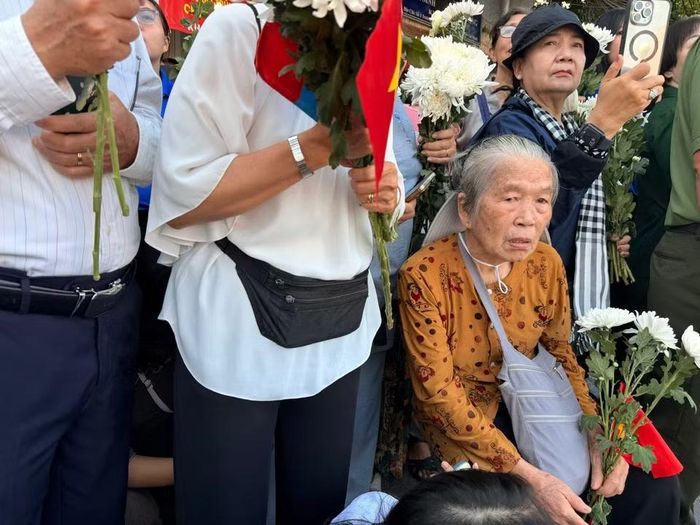 Cụ bà ngồi buồn, tiễn biệt đồng đội. (Ảnh: PV/Vietnam+)
