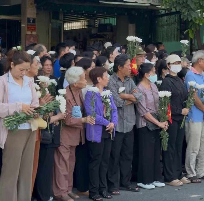 Dọc đường Trường Sơn, người dân đứng kín vỉa hè, cầm hoa trắng, cúi đầu khi đoàn xe đi qua. (Ảnh: PV/Vietnam+)