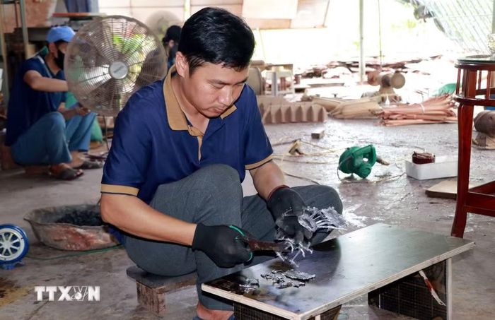 Anh Trần Văn Điệp, xã Cát Thành (Ninh Bình) chuẩn bị các chi tiết trang trí thân thuyền. (Ảnh: Nguyễn Lành/TTXVN)