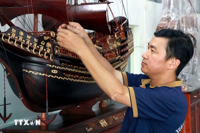 Anh Trần Văn Điệp, xã Cát Thành (Ninh Bình) căng chỉnh các dây buồm trên sản phẩm. (Ảnh: Nguyễn Lành/TTXVN)
