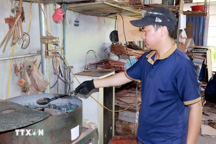 Anh Trần Văn Điệp, xã Cát Thành (Ninh Bình) đổ chì tạo các sản phẩm trang trí thuyền buồm. (Ảnh: Nguyễn Lành/TTXVN)