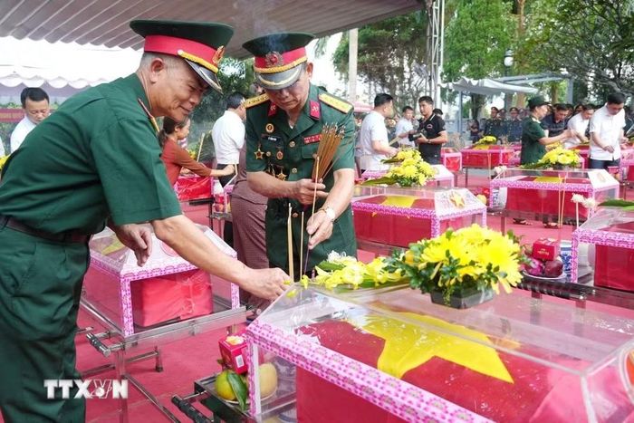 Những người lính năm xưa thắp hương trước linh cữu đồng đội tại Nghĩa trang liệt sỹ Quốc gia Vị Xuyên. (Ảnh: Minh Tâm/TTXVN)