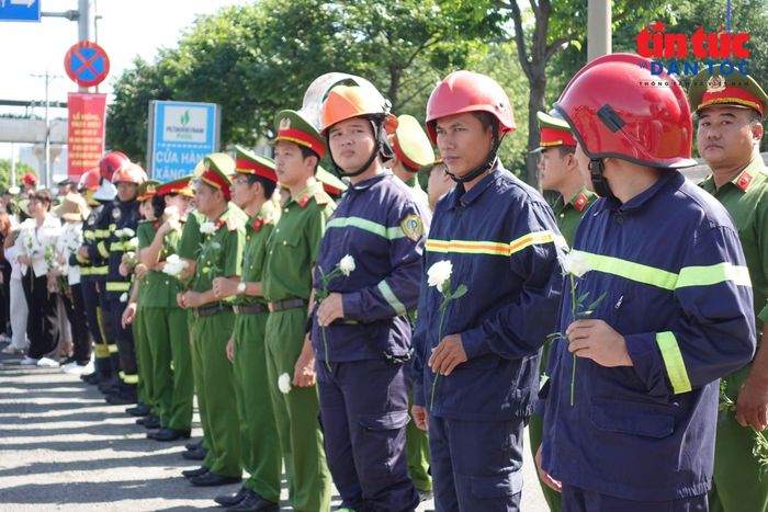 Các cán bộ chiến sĩ cảnh sát phòng cháy chữa cháy cầm cành hoa cúc trắng đứng tiễn biệt hai bên đường.