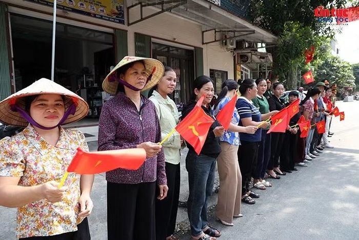 Phụ nữ xã Thanh Thủy cầm cờ Tổ quốc và cờ Đảng, đứng thành hàng dài bên đường chờ đón đoàn xe chở hài cốt liệt sĩ, thể hiện lòng thành kính đối với những người đã hy sinh vì Tổ quốc.