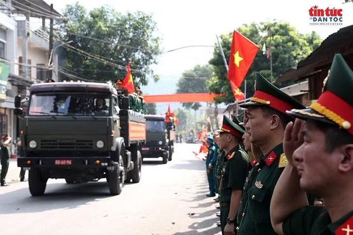 Đông đảo cán bộ, chiến sĩ và người dân đứng thành hàng dài dọc tuyến đường, cầm cờ Tổ quốc, thành kính tiễn đưa đoàn xe chở hài cốt liệt sĩ về Nghĩa trang Liệt sĩ Quốc gia Vị Xuyên.