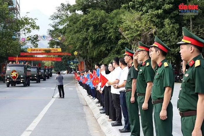 Cán bộ, chiến sĩ cùng đoàn viên, thanh niên và người dân đứng dọc tuyến phố, trang nghiêm chào đoàn xe chở hài cốt liệt sĩ trên hành trình về Nghĩa trang Liệt sĩ Quốc gia Vị Xuyên.