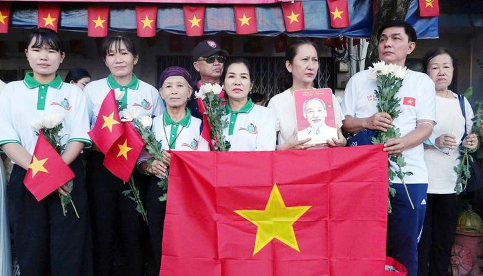 Người dân cầm hoa cúc trắng thành kính tiễn đưa các anh hùng liệt sĩ.
