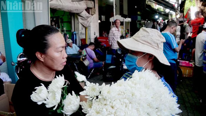Nhà ở phường Tây Thạnh, từ 4 giờ sáng, chị Nguyễn Thị Nhung (bên trái) cùng nhóm bạn đã có mặt tại Công viên Văn hóa Lê Thị Riêng cùng với hàng trăm đóa hoa cúc trắng, gửi tặng miễn phí người dân đến dự lễ viếng, truy điệu các liệt sĩ. (Ảnh: Báo Nhân dân)