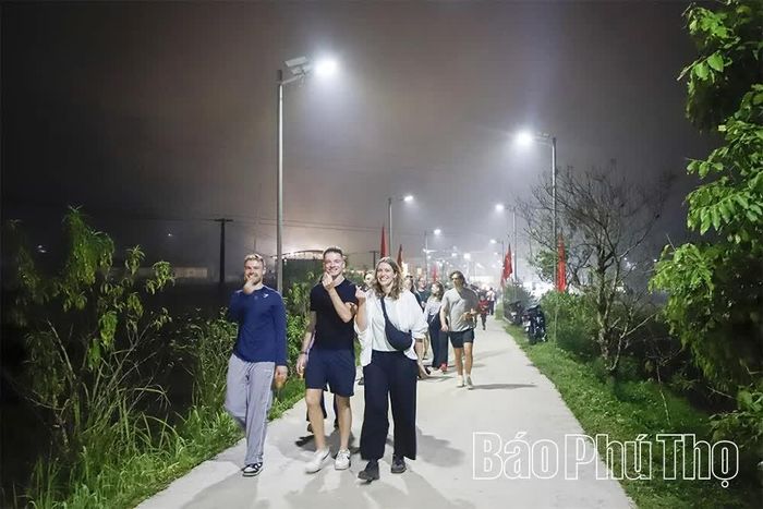 Du khách nước ngoài thích thú tham quan, trải nghiệm văn hóa bản địa tại các bản làng vùng cao Vân Sơn dưới ánh đèn đường rực sáng.