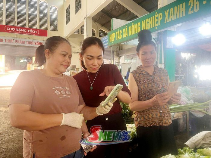 Đại diện Ban quản lý chợ hỗ trợ tiểu thương tại chợ Rặng Tếch sử dụng ứng dụng eTax Mobile.
