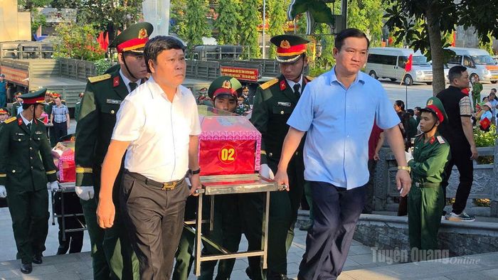 Đại biểu cùng các lực lượng đưa hài cốt liệt sĩ về nơi tập kết tại Nghĩa Trang. Ảnh: Thanh Phúc