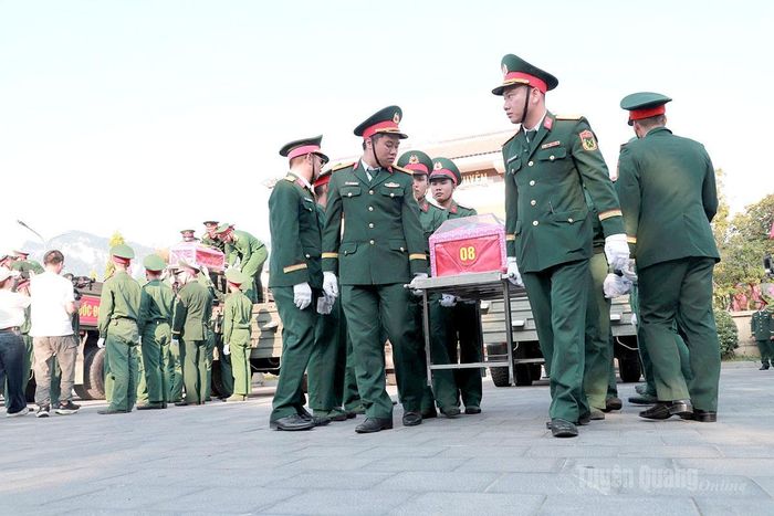Các lực lượng đưa hài cốt các Anh hùng liệt sĩ xuống xe tại Nghĩa trang Liệt sĩ Quốc gia Vị Xuyên. Ảnh: Phi Anh