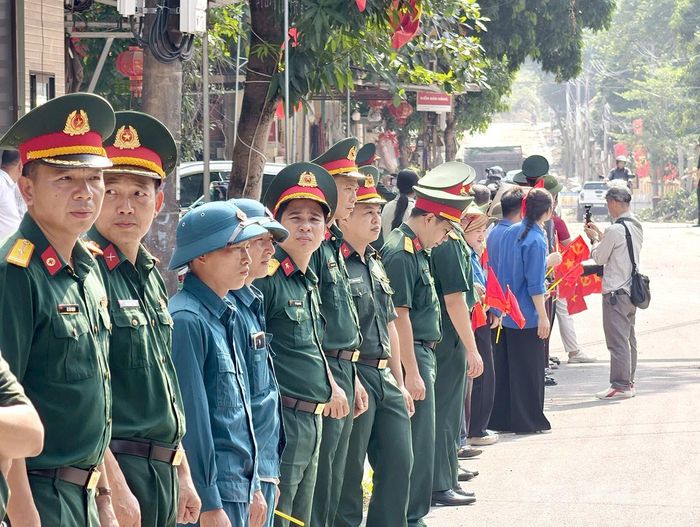 Lực lượng chức năng cùng với nhân dân xã Thanh Thủy sẵn sàng đón đoàn xe di chuyển hài cốt đi qua. Ảnh: Hải Nam