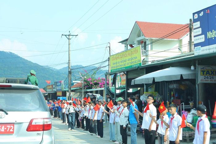 Học sinh xã Thanh Thủy vẫy cờ, xếp hàng ngay ngắn bên đường, thành kính chờ đón đoàn xe đưa các Anh hùng liệt sĩ trở về. Ảnh: Lý Thu