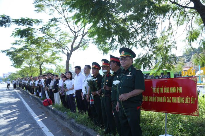 8h sáng, tại khu vực Khu du lịch Suối Tiên, đông đảo cựu chiến binh, người dân phường Tăng Nhơn Phú mang theo hoa cúc trắng, đứng thành hàng dọc bên đường Xa lộ Hà Nội chờ đưa tiễn các Anh hùng liệt sĩ. Ảnh: Văn Dũng