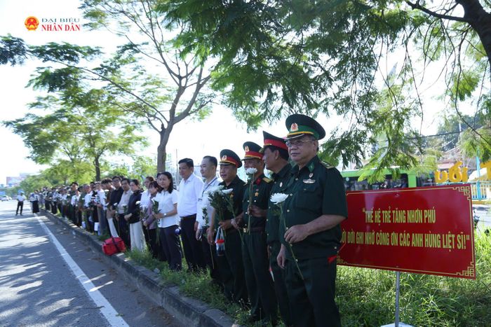 8h sáng, tại khu vực Khu du lịch Suối Tiên, đông đảo cựu chiến binh, người dân phường Tăng Nhơn Phú mang theo hoa cúc trắng, đứng thành hàng dọc bên đường Xa lộ Hà Nội chờ đưa tiễn các Anh hùng liệt sĩ. Ảnh: Văn Dũng
