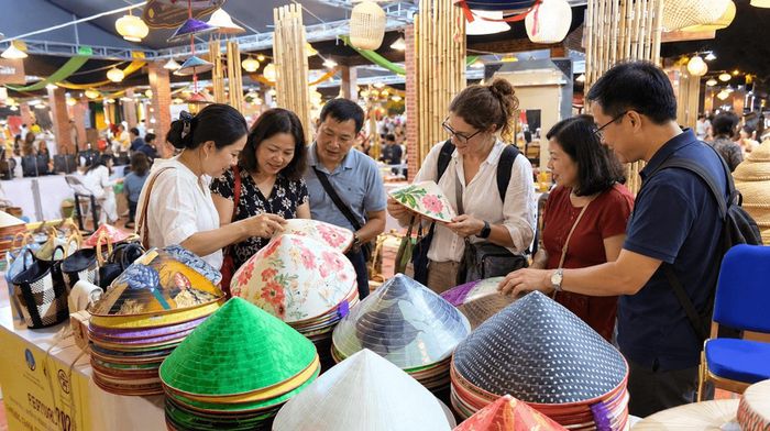 Du khách tham quan, tìm hiểu các sản phẩm nón truyền thống tại gian hàng làng nghề.