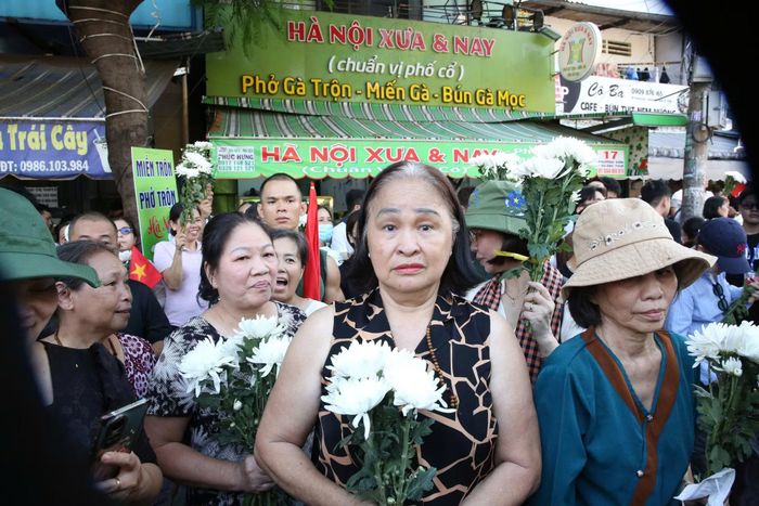 Bà Nguyễn Thị Nga (ngụ phường Hòa Hưng) cùng hàng xóm cầm nhành hoa trắng đưa tiễn các anh hùng liệt sĩ.