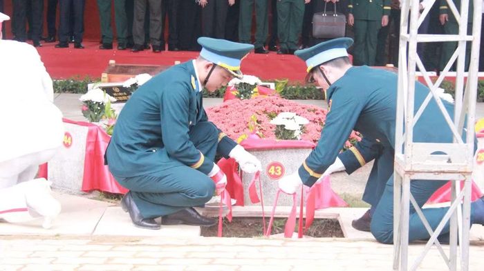 Lực lượng chức năng thực hiện nghi thức hạ huyệt hài cốt liệt sĩ tại Nghĩa trang liệt sĩ thành phố.