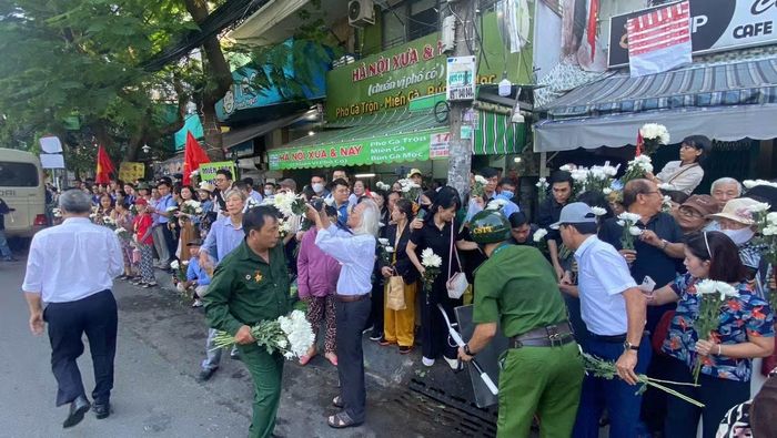 Cán bộ Công an hướng dẫn người dân xếp hàng chờ đoàn xe đưa các Anh hùng liệt sĩ đến nơi an táng.