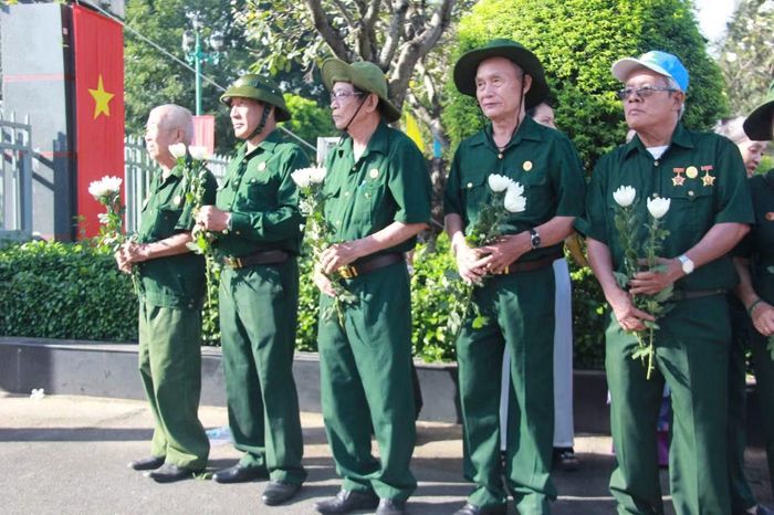 Các cựu chiến binh trên tay cầm những bông hoa trắng để tiễn đưa các Anh hùng liệt sĩ.