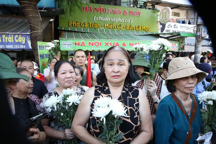 Bà Nguyễn Thị Nga (người dân ngụ tại phường Hòa Hưng) tay cầm nhành hoa trắng trong niềm xúc động khi cùng những người hàng xóm đứng hai bên đường đưa tiễn các anh hùng liệt sĩ.