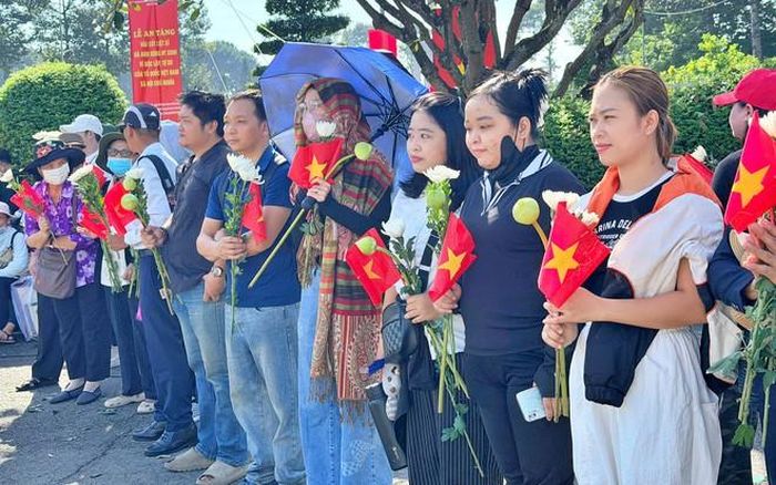 Người dân và học sinh trang nghiêm chờ đoàn xe đưa hài cốt liệt sĩ về nơi an nghỉ.