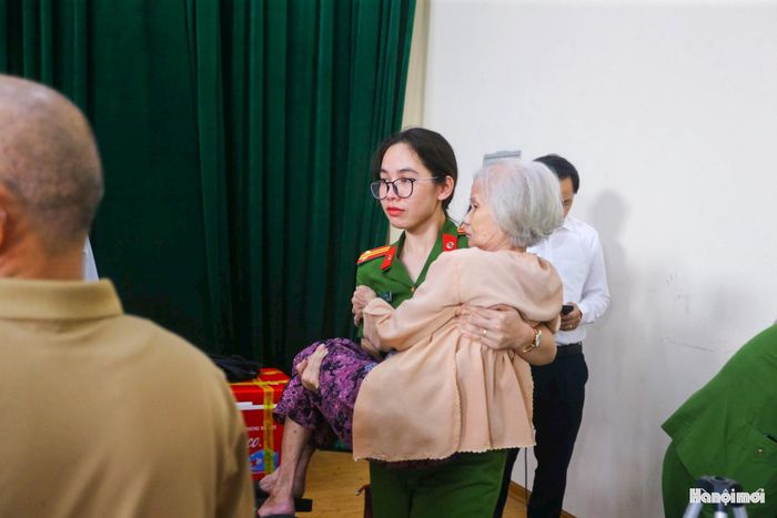 Khoảnh khắc nữ chiến sĩ Cảnh sát khu vực bế cụ bà thân nhân liệt sĩ tuổi cao sức yếu vào khu vực lấy mẫu khiến nhiều người có mặt trong hội trường không khỏi xúc động