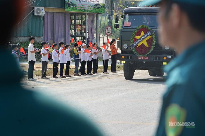 Các em học sinh thành kính chào đón đoàn xe chở hài cốt liệt sĩ. Ảnh: Tuấn Anh