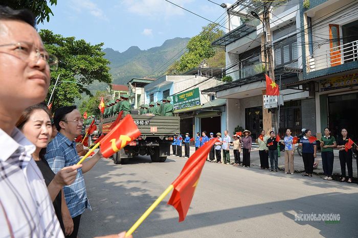 Người dân đứng hai bên đường, dõi theo đoàn xe đưa hài cốt liệt sĩ trở về. Ảnh: Tuấn Anh