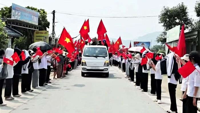 Đông đảo người dân, học sinh cầm cờ đón liệt sĩ Nguyễn Xuân Nhị trở về quê hương. (Ảnh: DP)