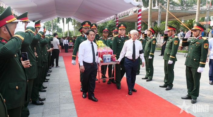 Các đại biểu cùng cán bộ, chiến sĩ lực lượng vũ trang thực hiện nghi thức đưa hài cốt liệt sĩ về nơi an nghỉ cuối cùng.  